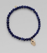 The open hand or hamsa, a symbol of protection to many cultures, is depicted in diamonds set in 14k yellow gold with a sapphire center, and hangs on a strand of deeply hued sodalite beads. Diamonds, 0.04 tcw Sapphire Sodalite 14k yellow gold Diameter, about 2 Charm length, about ½ Stretch cord Imported