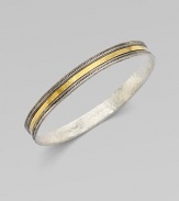 From the Lancelot Collection. Thoroughly modern and thoroughly stunning, this slender bangle of hammered sterling silver with ridged and fluted edges is encircled by a gleaming band of 24k gold.Sterling silver and 24k yellow goldDiameter, about 2½Imported