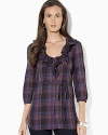 A bold plaid pattern sweeps across a chic cotton tunic, crafted with feminine ruffles at the neckline and three-quarter-length sleeves.