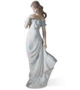 Draped in a flowing blue and white dress, this classical Lladro figurine pauses to admire a cluster of blooms amid a warm summer breeze.