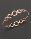 This sterling silver and rose gold bangle, adorned with chic circles, is beautiful alone or stacked.