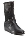 Crisscross elastic straps add edge to the sleek silhouette of these leather wedge boots. By Stuart Weitzman.