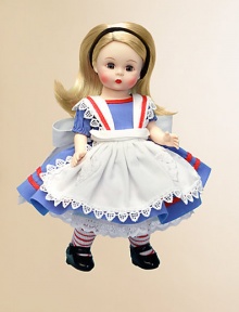 This doll has blue eyes and side-parted, long, ivory blonde hair that's held by a black velvet headband. She's dressed in a blue cotton dress that has short puffy sleeves and red soutache trim. Her white apron, edged with a scalloped lace trim, has red soutache trim on the straps and a heart shaped, appliquéd, lace pocket.