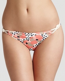 Beach roses bloom on a polka-dotted bikini bottom, finished with nautical rope side ties. By Juicy Couture.