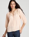 In a pale melon hue, Tucker's essential silk blouse gets a summer-ready update with smocked detailing.