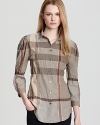 An elasticized waist and an A-line silhouette lend feminine spirit to the classic Burberry Brit check shirt. Style with dark denim and sleek flats for effortless polish.