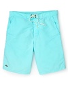 Hit the beach in these classic cut Lacoste swim trunks with the quintessential alligator logo at the hem.