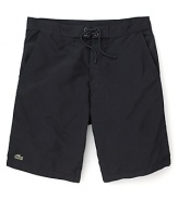 Hit the beach in these classic cut Lacoste swim trunks with the quintessential alligator logo at the hem.