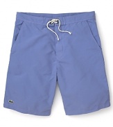 Hit the beach in these classic cut Lacoste swim trunks with the quintessential alligator logo at the hem.