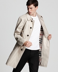 Covered placket long trench coat with zip out warmer. Check under stand collar. Side buttoned pockets. Button tab at cuffs.