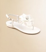 A graceful satin T strap blooms with a floppy flower of chiffon and tulle with a rhinestone center.Terylene satin upperT strap thong with flowerBuckle ankle strapFaux leather sole with rubber insertPadded insoleFaux leather liningImported