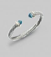 From the Silver Classics Collection. The signature Yurman cable bangle, capped with faceted blue topaz domes and accents of 14k gold. Blue topaz Sterling silver and 14k yellow gold Cable, 7mm Diameter, about 2¼ Imported