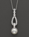 A pearl drop pendant is dropped from a diamond-accented teardrop design.