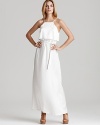 A white Kimberly Taylor maxi dress imbues your day with beachy sensibility, light and airy with a ruffle at top and a flowing skirt. Nude sandals complete the ethereal look with chic.