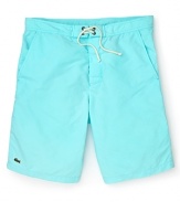 Hit the beach in these classic cut Lacoste swim trunks with the quintessential alligator logo at the hem.