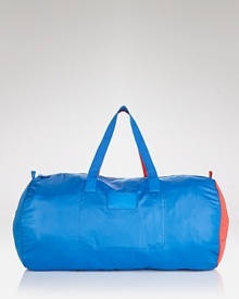 Not your basic weekender: trend-right cobalt and red accents embolden this MARC BY MARC JACOBS duffel bag that packs away for a convenient (and colorful) statement.