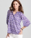 In a rich ikat print and a royal purple hue, this Aqua blouse lends luxe style.