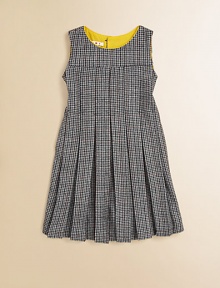 A retro, school-girl design in houndstooth goes modern with colorful piping at the neckline. Houndstooth patternRound neckline with contrast pipingSleevelessPleated bodice and skirtFit and flare silhouetteBack button closure50% fleece wool/50% viscoseMachine washMade in Italy