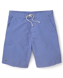 Hit the beach in these classic cut Lacoste swim trunks with the quintessential alligator logo at the hem.