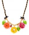 Garden variety. A trio of beautiful blooms adorns this sweet statement necklace from Betsey Johnson. Embellished with sparkling crystals, bows, leaves, an intertwined grosgrain ribbon and a charming ladybug, it's made in antique gold tone mixed metal. Approximate length: 16 inches + 3-inch extender.