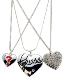 Triple the romance. GUESS's chic, three-row necklace features shiny hearts featuring a red enamel question mark, the signature logo and sparkling crystals. Crafted in silver tone mixed metal. Approximate length: 16 inches + 2-inch extender. Approximate drop: 1-1/2 inches.