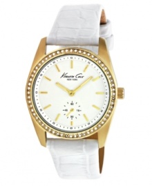 Golden glamour set against crisp, clean white. Watch by Kenneth Cole New York crafted from white croc-embossed leather strap and round gold ion-plated stainless steel case. Bezel embellished with ring of crystal accents. White dial features gold tone stick indices, black minute track, second subdial at six o'clock, luminous gold tone hands, and logo. Quartz movement. Water resistant to 30 meters. Limited lifetime warranty.