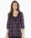 A bold plaid pattern sweeps across Lauren Jeans Co.'s chic cotton tunic, crafted with feminine ruffles at the neckline and three-quarter-length sleeves.