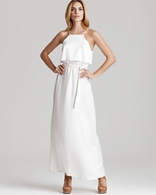 A white Kimberly Taylor maxi dress imbues your day with beachy sensibility, light and airy with a ruffle at top and a flowing skirt. Nude sandals complete the ethereal look with chic.