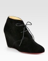 Trend-forward suede ankle boot has a lace-up front, self-covered wedge and signature red leather sole. Self-covered wedge, 3 (75mm)Suede upperLeather liningSignature red leather solePadded insoleMade in ItalyOUR FIT MODEL RECOMMENDS ordering one half size up as this style runs small. 