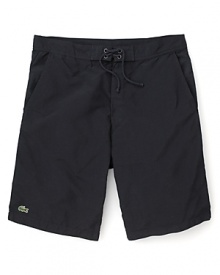 Hit the beach in these classic cut Lacoste swim trunks with the quintessential alligator logo at the hem.