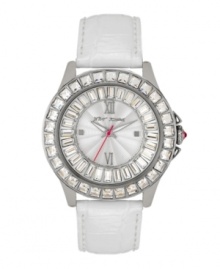 Ice makes everything hotter. Betsey Johnson watch crafted of white leather strap and round stainless steel case. Bezel embellished with crystal accents. Textured silver tone dial features ring of baguette-cut crystal accents, applied silver tone Roman numerals at twelve and six o'clock, dot markers at three and nine o'clock, luminous hour and minute hands, signature fuchsia second hand and logo. Quartz movement. Water resistant to 30 meters. Two-year limited warranty.