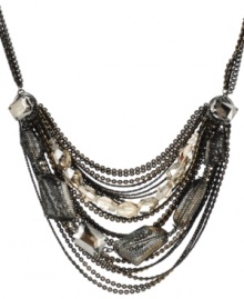 Decoratively draped. Layered rows of chains combine with faceted glass accents (some wrapped in black netting) on Kenneth Cole New York's striking statement necklace. Made in hematite tone mixed metal. Approximate length: 16 inches + 3-inch extender.