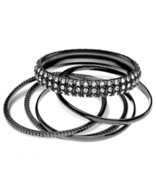 Sleek and stylish, this set of five bangles from GUESS is crafted from hematite-tone mixed metal. Glass crystal stones add a chic touch. Approximate diameter: 1-1/2 inches.