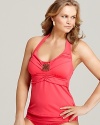 A flattering halter silhouette from Becca Etc. is dressed up with an ornate, brass-tone charm and foldover detailing.