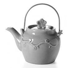 Crafted by hand of weighty ceramic with a glossy glaze, the Laces Teapot from Mateus showcases subtle variations in color that highlight a dimensional flowering branch motif.