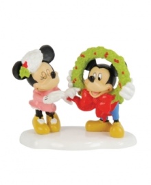 Mickey and Minnie flirt with a little Christmas romance, giggling as they put the finishing touches on a Mickey's Village holiday wreath. By Department 56.