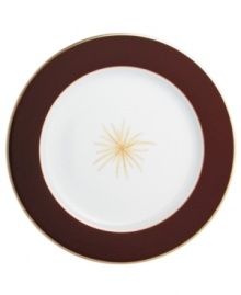 A rich burgundy rim frames a single gold starburst in the center of this striking service plate from Bernardaud.