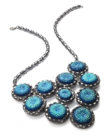 Go for glitter and perfect your party look. This festive bib necklace boasts rows of blue plastic cabochon stones with a glittery finish. Crafted in hematite tone mixed metal. Approximate length: 18 inches + 2-inch extender. Approximate drop: 3 inches.